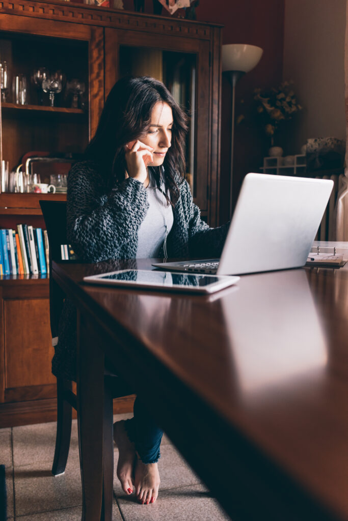 Business owner working on a laptop while speaking on the phone in a modern office